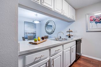 A kitchen with white cabinets and a wooden cutting board on the counter.